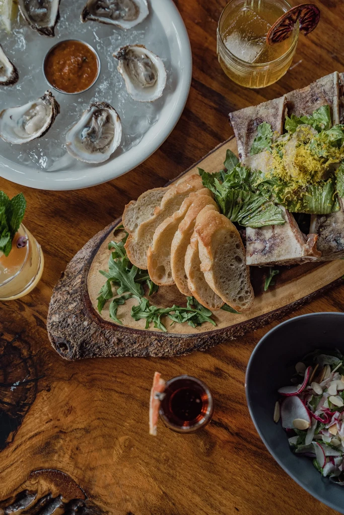 Overhead shot of diverse dishes and cocktails on a rustic wooden table.