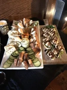 Two platters of appetizers: crostini, dips, and small sandwiches.