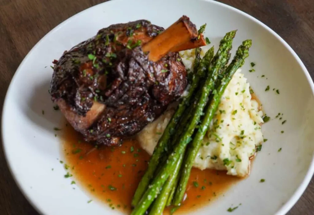 Close-up: Braised meat shank, mashed potatoes, asparagus, and gravy.