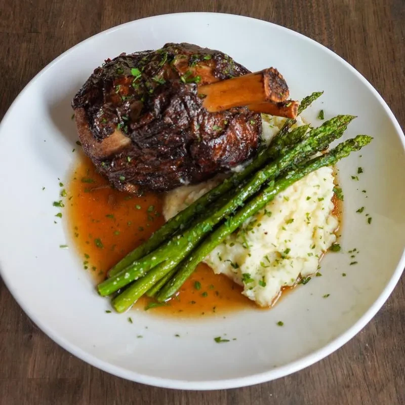 Braised meat, mashed potatoes, and asparagus professionally plated.