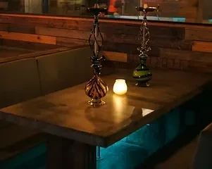Two ornate hookahs on a table in a dimly lit lounge.
