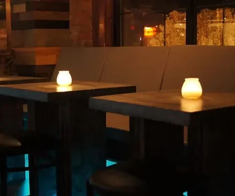 Intimate restaurant setting with candlelit tables and subtle blue lighting.