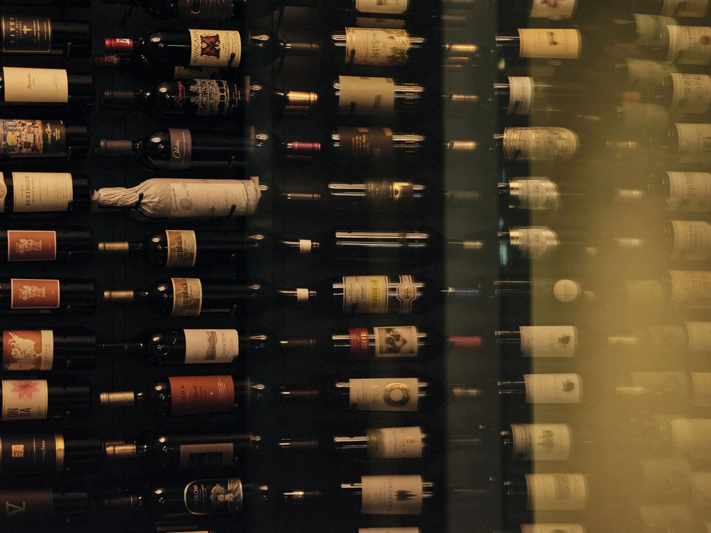 A large rack of wine bottles, with clear and blurred labels.