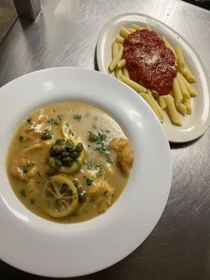 Chicken piccata and penne pasta dishes on a kitchen counter.