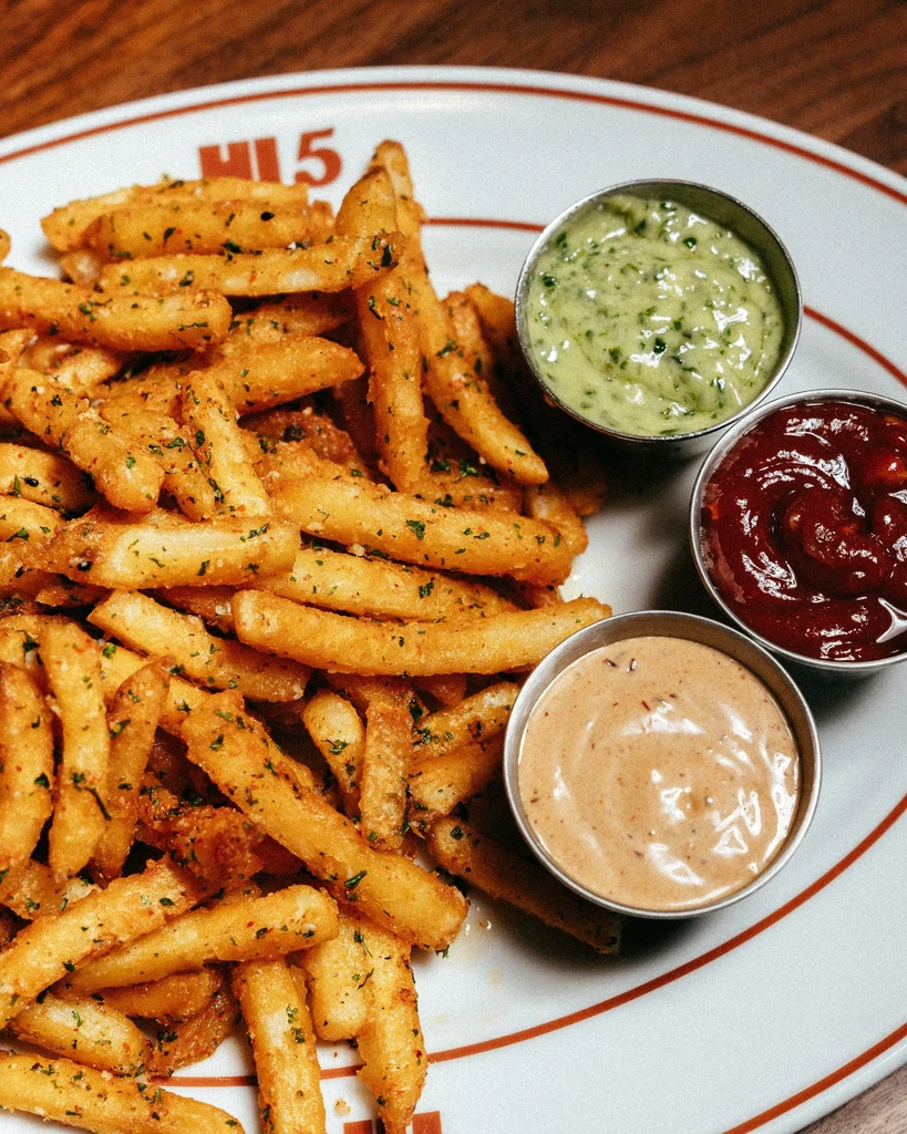 Golden-brown herb fries with light green, red, and brown dipping sauces.