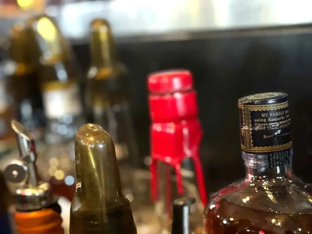 Close-up of dimly lit liquor bottles, one labeled 'MY FAMILY Kentucky'.