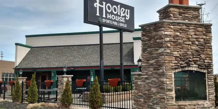 Hooley House Sports Pub exterior with sign, building, and outdoor fireplace.