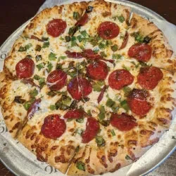 Sliced pepperoni pizza with melted cheese and green peppers.