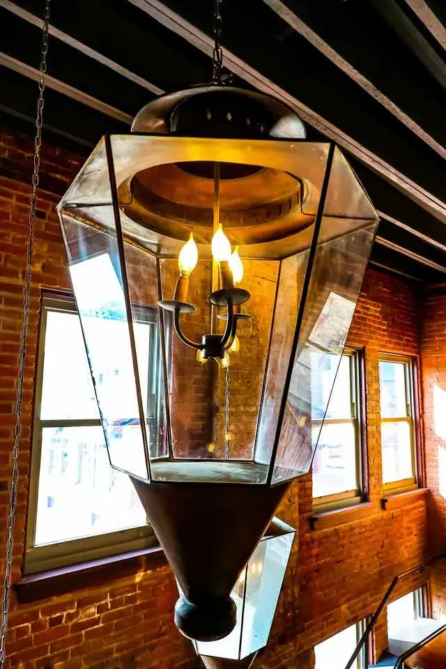 Hanging geometric dark metal fixture with glass panels and three bulbs.