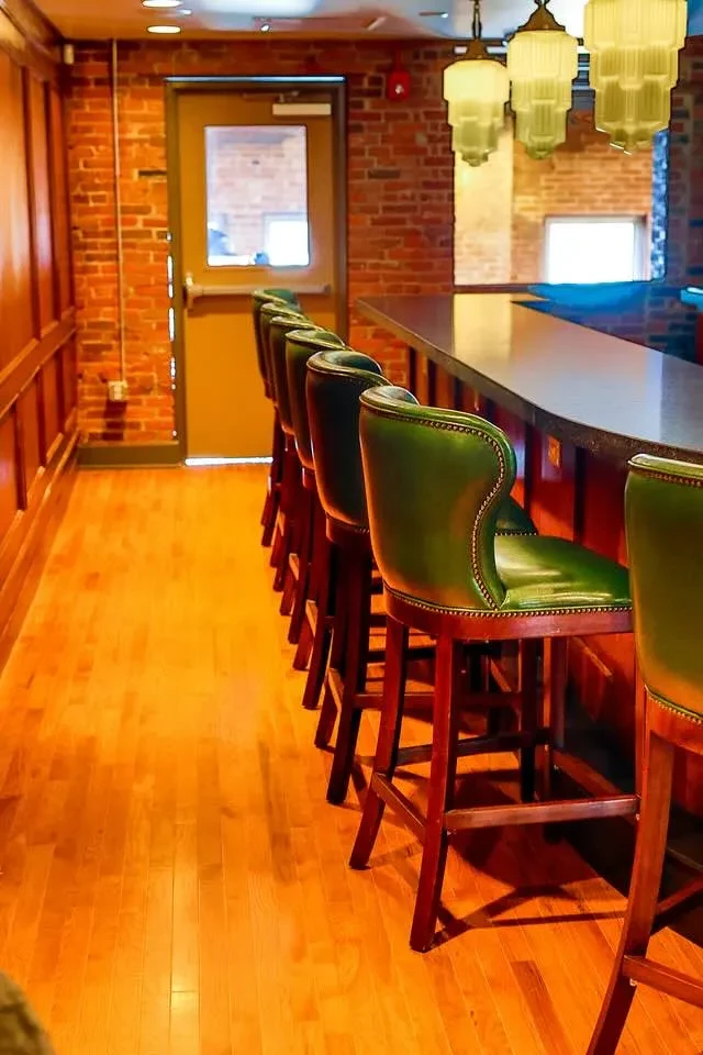 Empty classic bar with dark green studded bar stools.