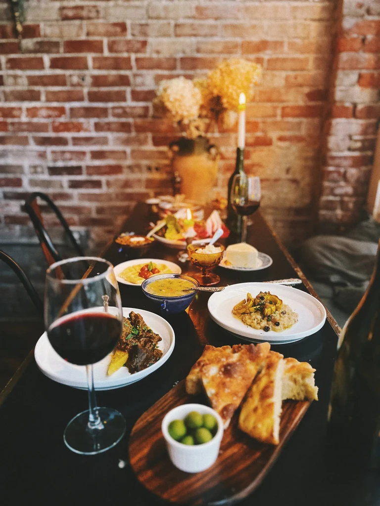Cozy restaurant table with small plates of food, wine, and candle.