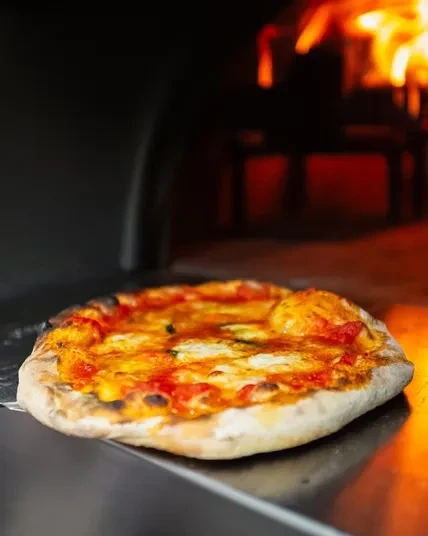 Freshly baked Margherita pizza with charred crust, glowing oven background.