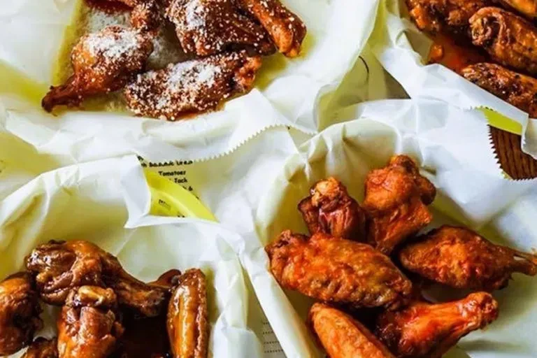 Multiple servings of chicken wings with various sauces and seasonings.