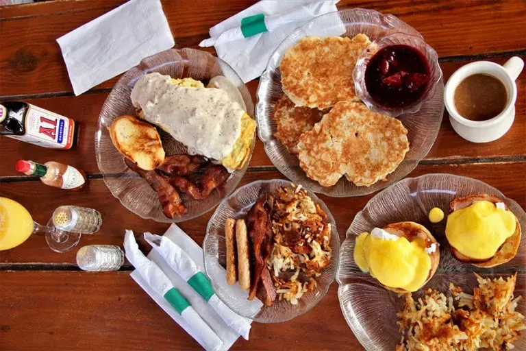 Overhead view of various breakfast dishes on a rustic wooden table.