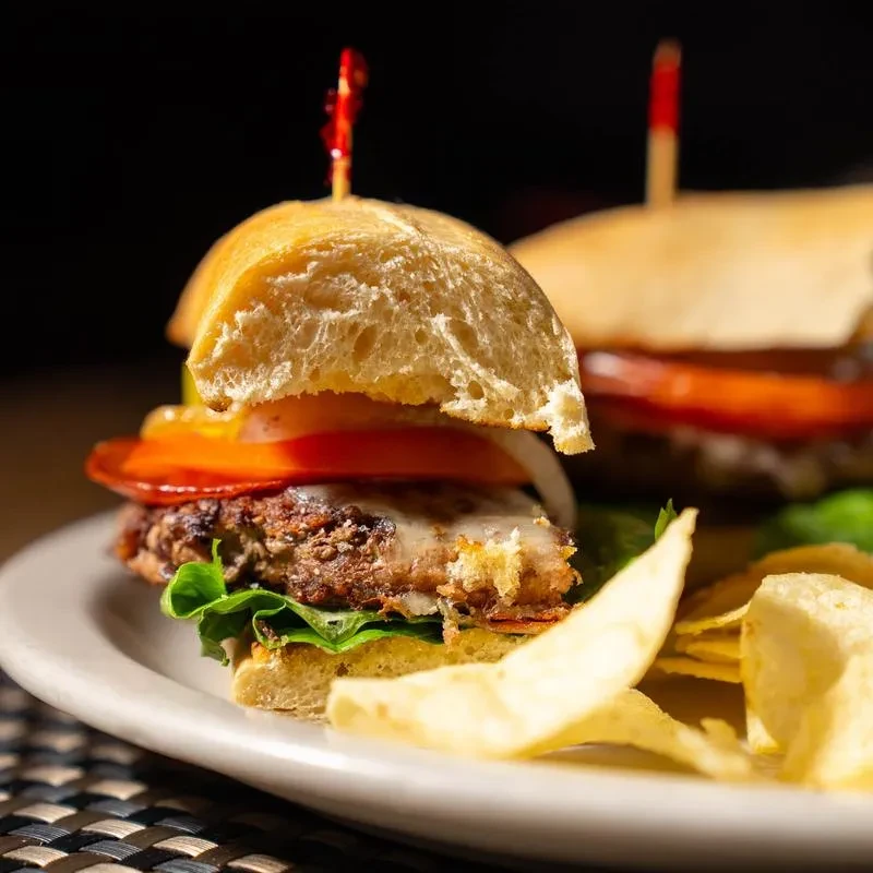 Two gourmet sliders with lettuce, tomato, onion, and potato chips.