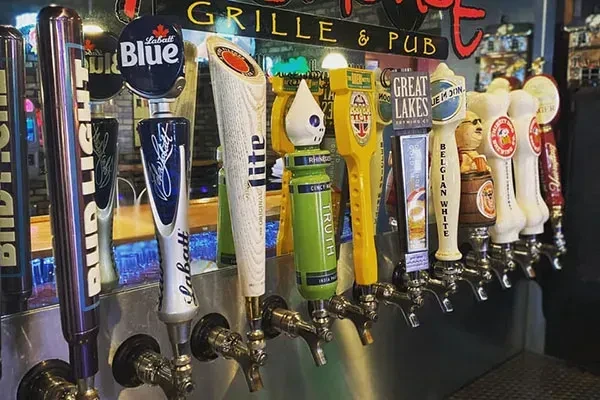 Close-up of various branded beer tap handles in a pub.