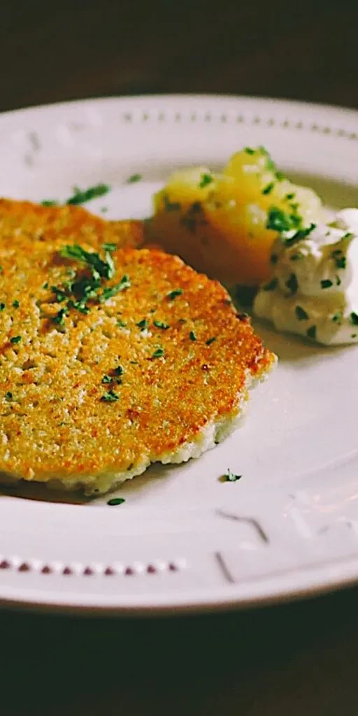 Golden-brown potato pancake, side potatoes, and creamy sauce with herbs.