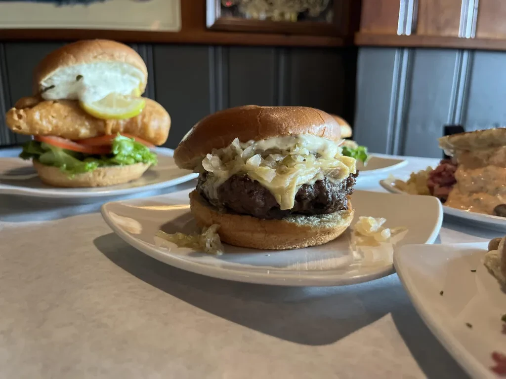 Close-up of a cheeseburger, fish sandwich, and another sandwich in a restaurant.
