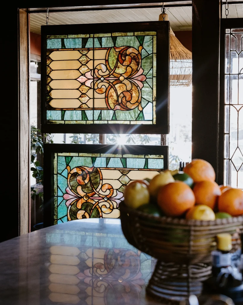 Sunlit stained glass panels with a citrus fruit bowl reflecting them.