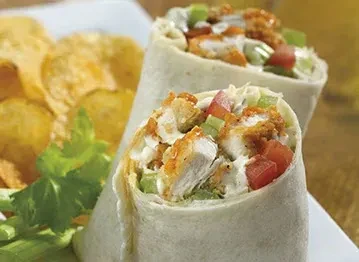 Crispy chicken wraps with tomatoes, greens, sauce, and potato chips.