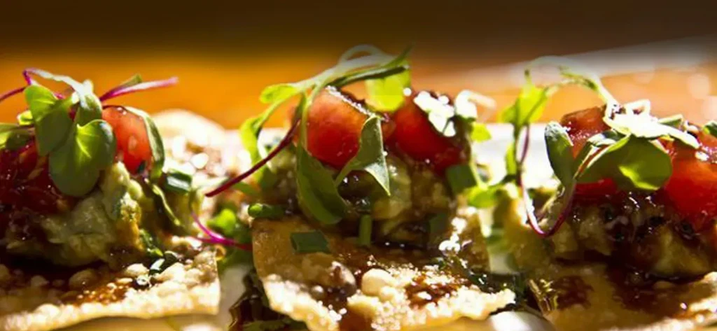 Crispy guacamole appetizers with tomatoes, microgreens, and sauce.