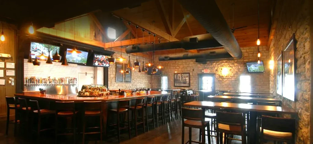 Empty bar and restaurant with wooden counter, beer taps, and tables.