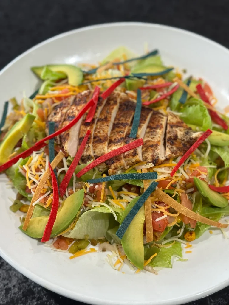 Grilled chicken salad, avocado, cheese, tomatoes, colorful tortilla strips.