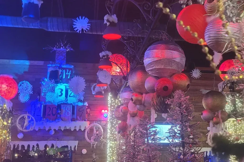 Heavily decorated interior with holiday lights, lanterns, advent calendar, snow.