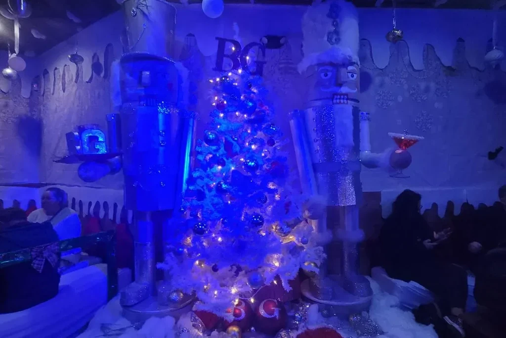 Two metallic nutcrackers flank a white Christmas tree in blue lighting.