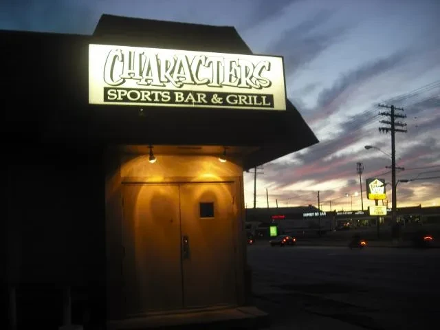 CHARACTERS SPORTS BAR & GRILL illuminated sign and exterior at dusk.