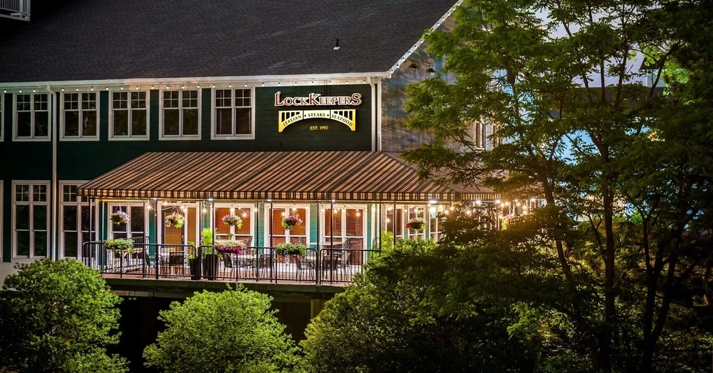 LockKeepers restaurant with dark green siding and illuminated outdoor patio at night.