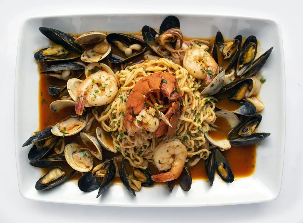 Seafood pasta with halved lobster, shrimp, mussels, and clams.