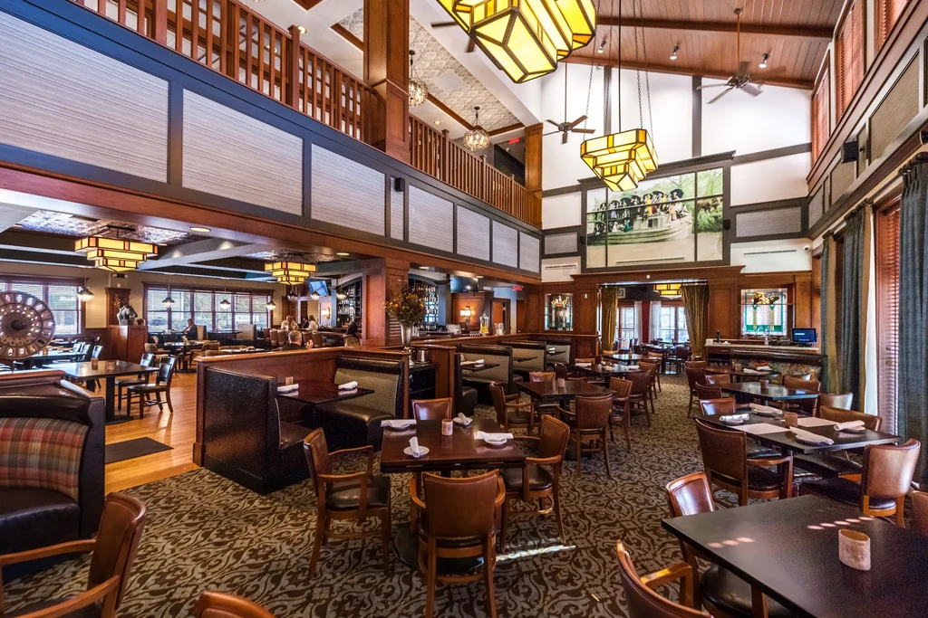 Upscale multi-level restaurant interior with wood, leather, and a large mural.