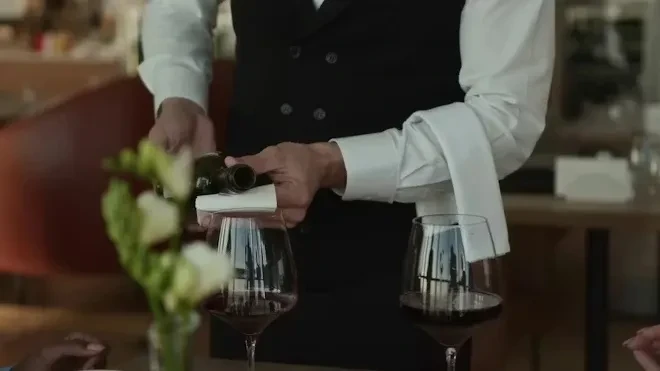 Close-up: Server pouring red wine into glass at restaurant.