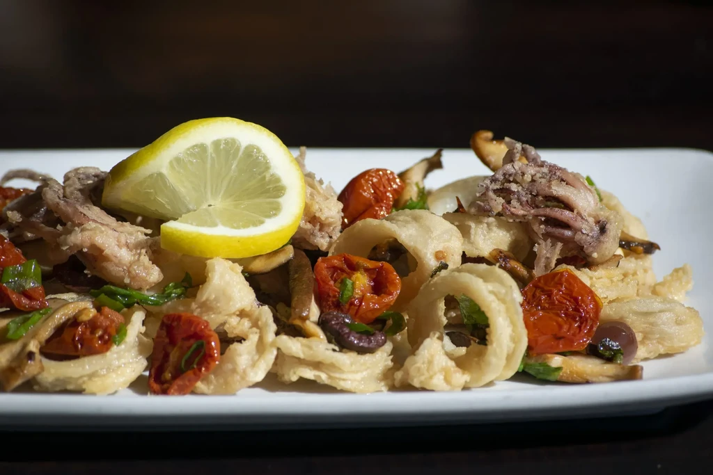 Fried seafood medley with roasted vegetables, lemon, and herbs.