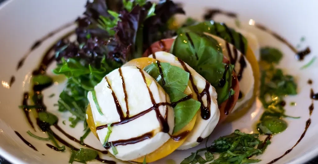 Caprese salad with stacked mozzarella, yellow tomatoes, basil, and balsamic.