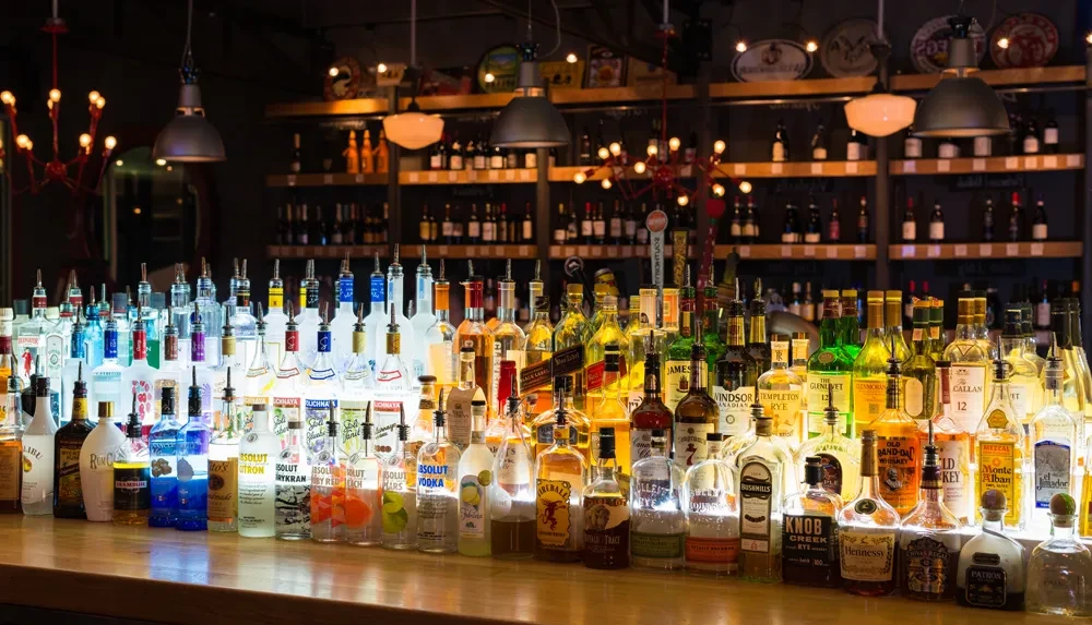 Vibrant, well-stocked bar counter with backlit liquor bottles.