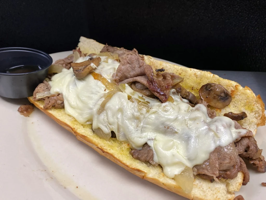 Cheesesteak sub with melted cheese, caramelized onions, mushrooms, and au jus.