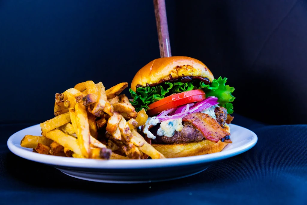 Studio shot: gourmet blue cheese bacon burger and fries.
