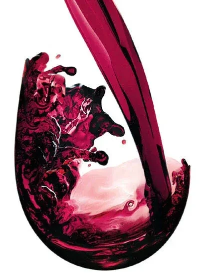 Red wine pours into a clear glass, creating vivid splashes.