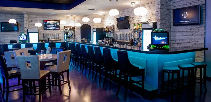 Blue LED-lit bar counter inside a modern, well-stocked restaurant.