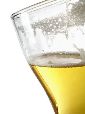 Golden beer in a clear glass with foam and lacing.