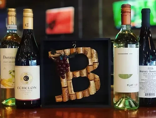 Four wine bottles, two light, two dark, with a cork 'B'.