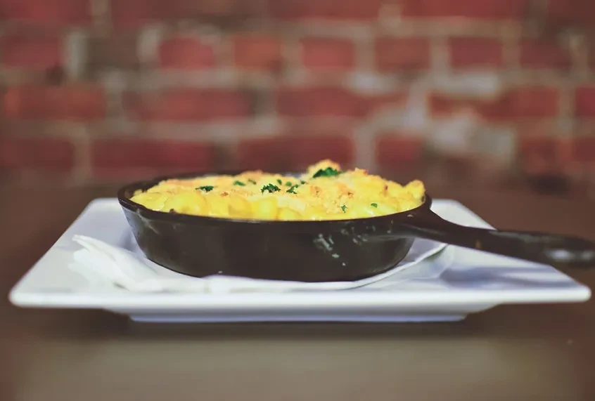 Golden mac and cheese with crispy crust in a cast iron pan.