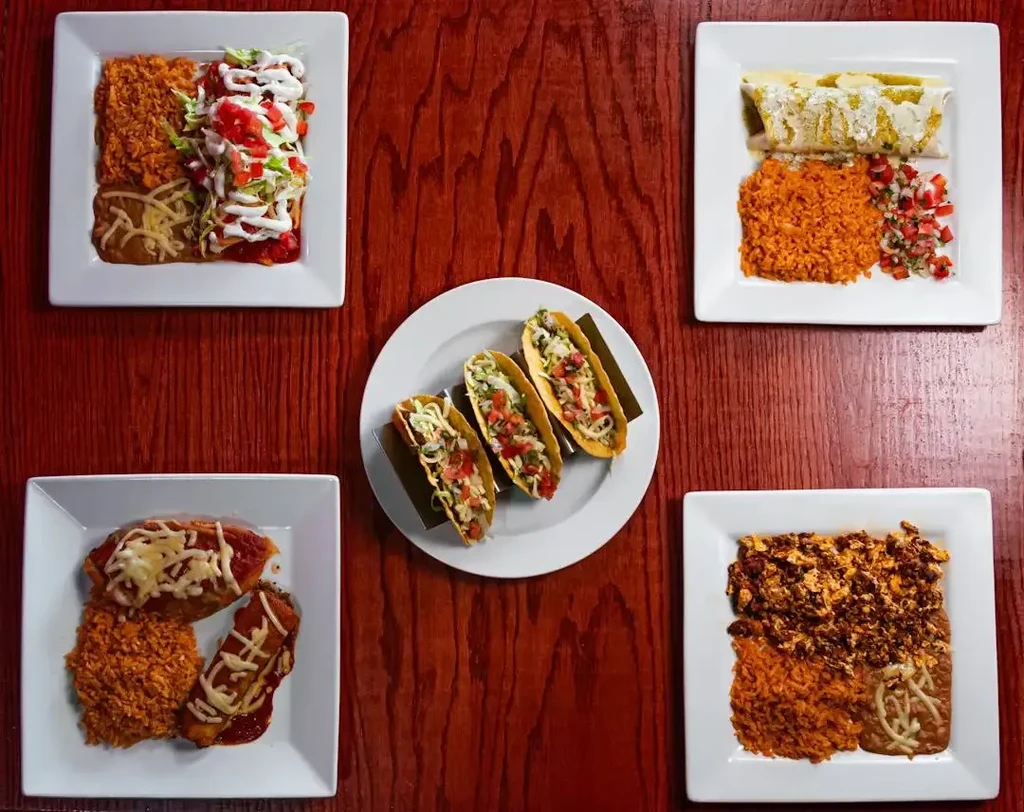 Six plates of Mexican food: tacos, enchiladas, eggs, rice, and beans.
