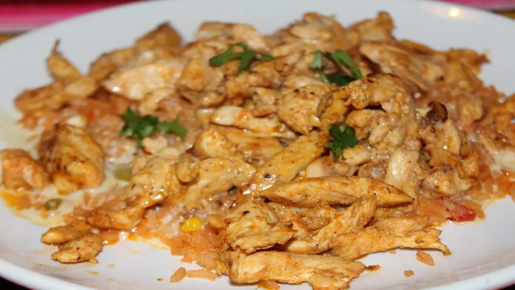 Shredded chicken and Mexican rice with creamy sauce, garnished with cilantro.