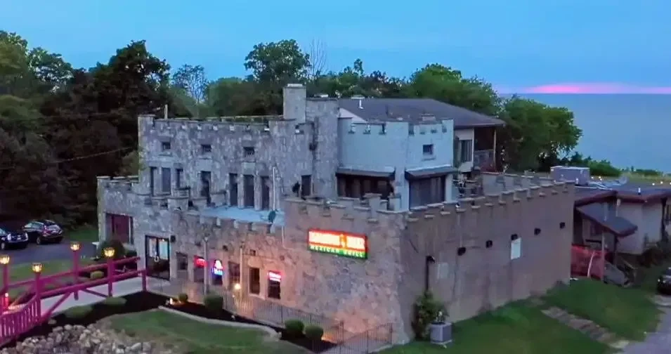Castle-like building with a 'Mexican Grill' sign, pink bridge, and twilight sky.