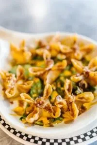 Golden-brown fried wontons with sauce and herbs, checkerboard plate.