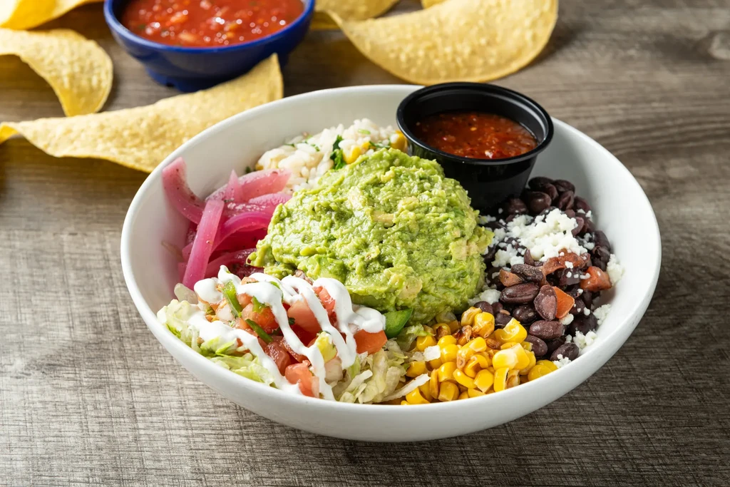 Colorful burrito bowl with guacamole, black beans, corn, and salsa.