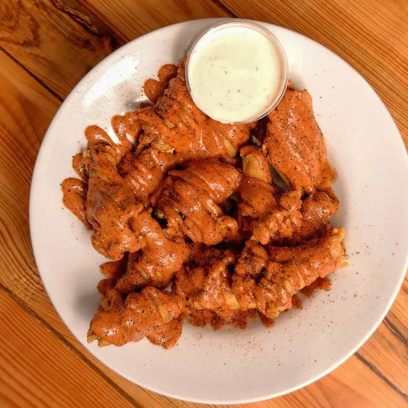 Plate of red-sauced chicken wings and creamy white dipping sauce.